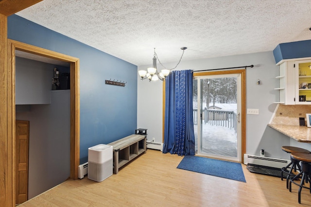 entryway with light hardwood / wood-style floors, baseboard heating, a textured ceiling, and a notable chandelier