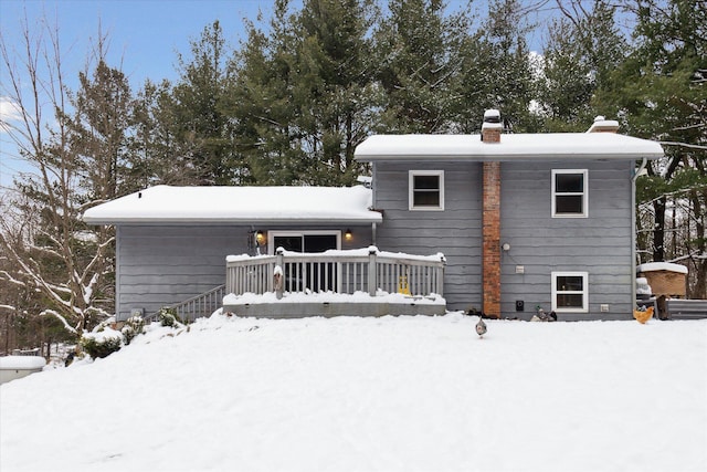 snow covered rear of property with a wooden deck