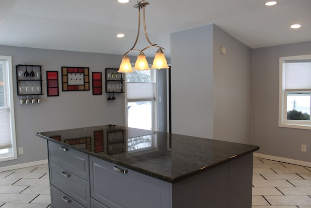 kitchen featuring plenty of natural light, pendant lighting, a center island, and dark stone countertops