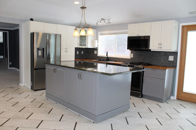 kitchen with decorative light fixtures, white cabinets, appliances with stainless steel finishes, and a kitchen island