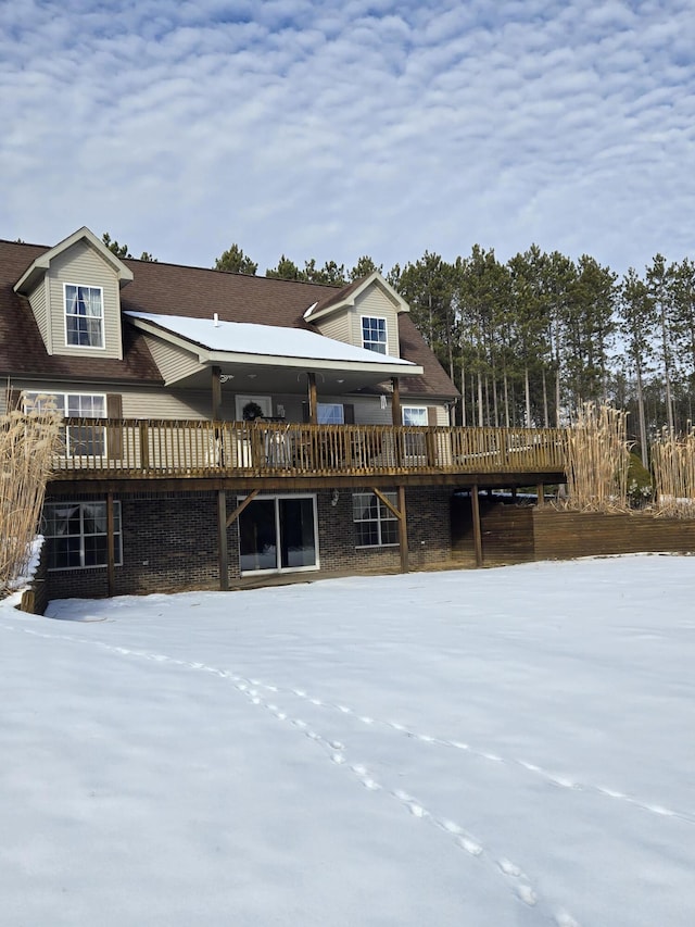 snow covered back of property with a wooden deck