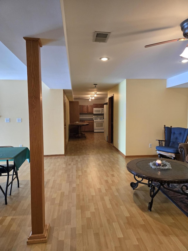 hall with ornate columns and light wood-type flooring