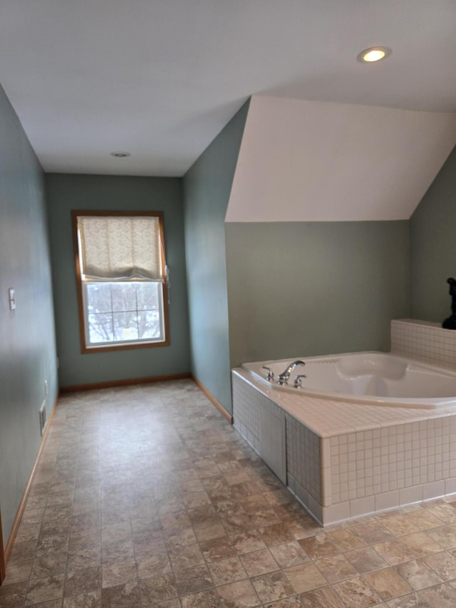 bathroom featuring lofted ceiling and tiled tub