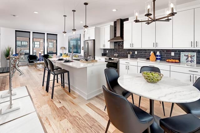 kitchen featuring hanging light fixtures, a center island with sink, stainless steel appliances, and white cabinetry