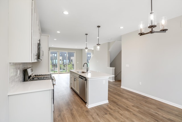 kitchen with white cabinetry, an island with sink, stainless steel appliances, pendant lighting, and sink