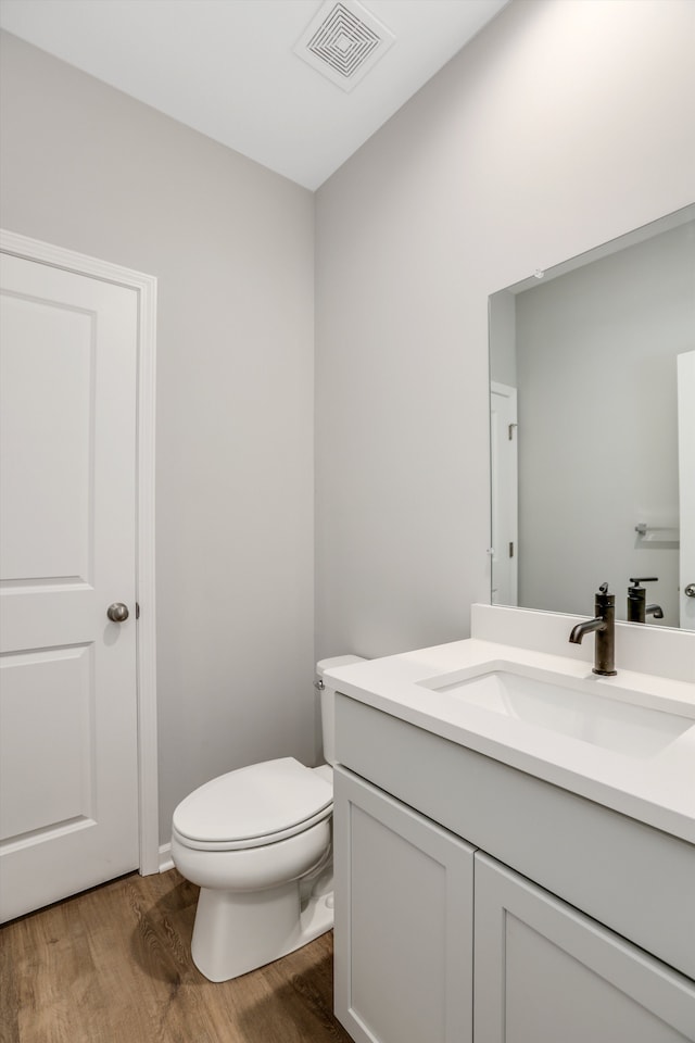 bathroom featuring toilet, vanity, and wood-type flooring