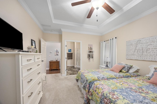 carpeted bedroom with ceiling fan, ensuite bath, crown molding, and a raised ceiling