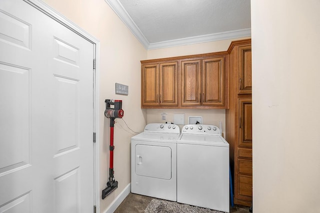 laundry area featuring washing machine and dryer, a textured ceiling, ornamental molding, and cabinets