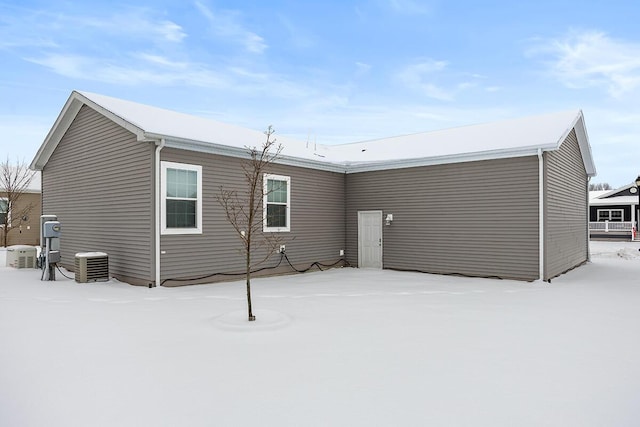 snow covered back of property featuring central AC