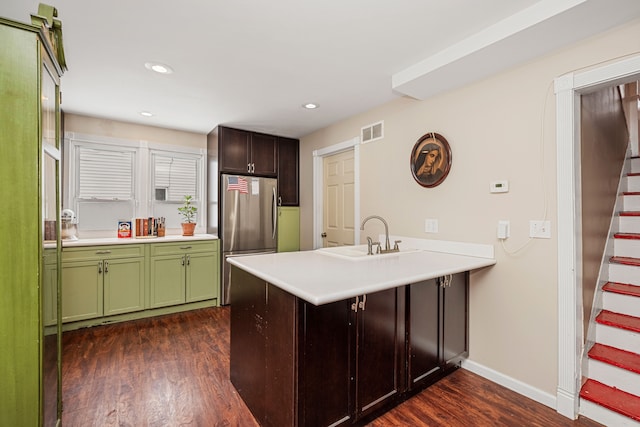 kitchen featuring kitchen peninsula, stainless steel refrigerator, dark hardwood / wood-style flooring, green cabinetry, and sink