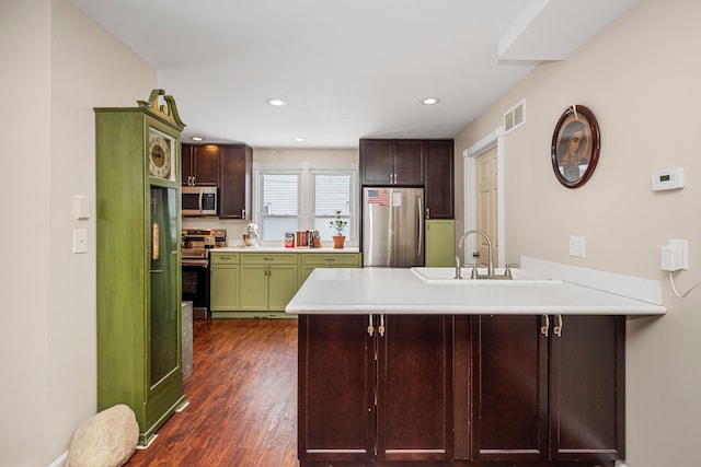 kitchen featuring kitchen peninsula, appliances with stainless steel finishes, dark hardwood / wood-style flooring, green cabinetry, and sink