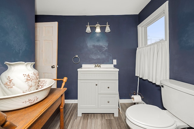 bathroom featuring wood-type flooring, toilet, and vanity