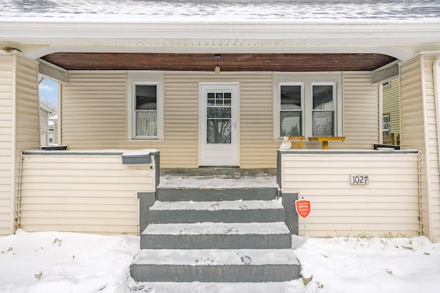 snow covered property entrance featuring a porch