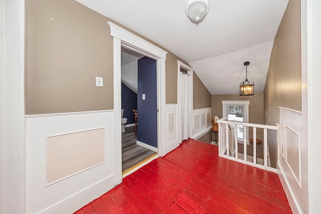 corridor with an inviting chandelier and lofted ceiling