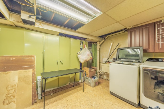 basement with a drop ceiling and washing machine and clothes dryer