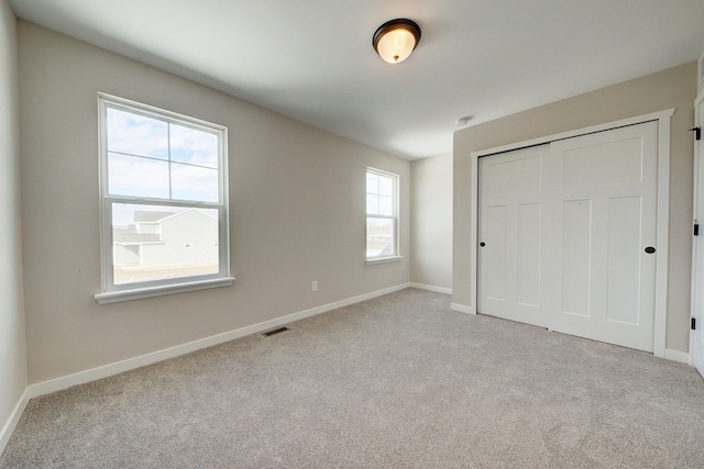 unfurnished bedroom featuring light carpet and a closet