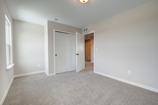 unfurnished bedroom with light colored carpet and a closet