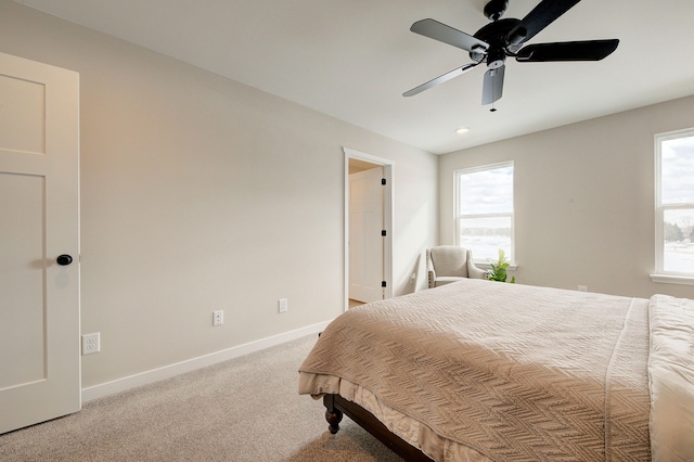 bedroom featuring ceiling fan, light carpet, and multiple windows