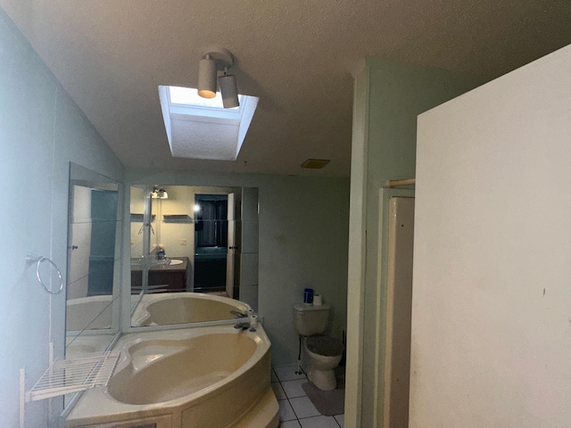 bathroom with toilet, vaulted ceiling with skylight, tile patterned floors, and a tub to relax in