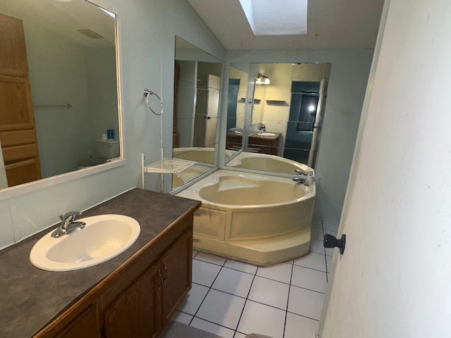 bathroom featuring a bathtub, vaulted ceiling with skylight, tile patterned floors, and vanity