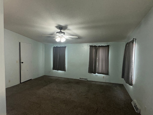 empty room with a textured ceiling, ceiling fan, and carpet