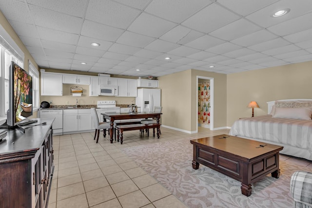 tiled bedroom with sink, a drop ceiling, and white fridge with ice dispenser