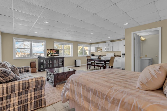 bedroom featuring light tile patterned floors, white fridge with ice dispenser, and a drop ceiling