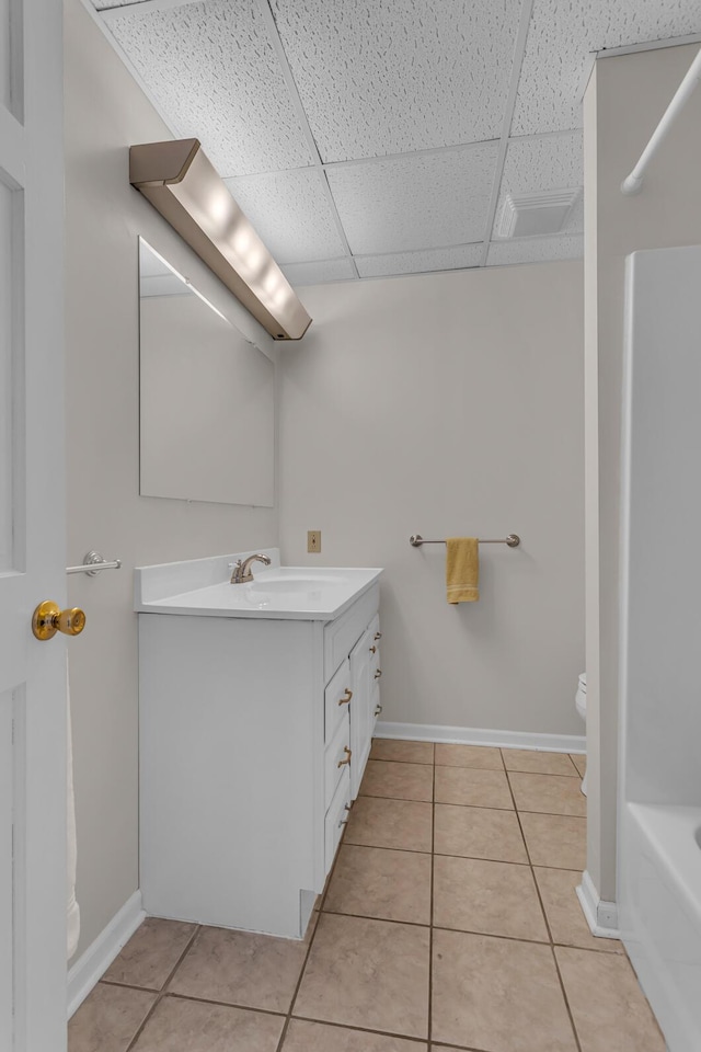 bathroom with a paneled ceiling, a bathtub, tile patterned floors, and vanity