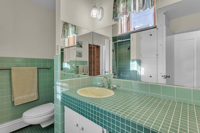 bathroom featuring toilet, tile patterned flooring, tile walls, and vanity