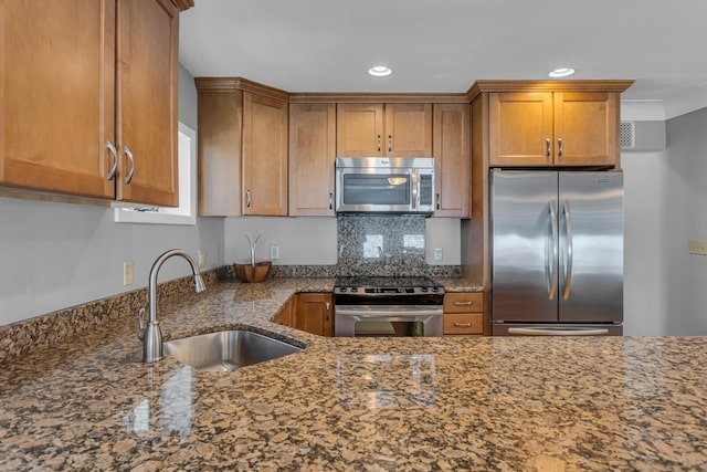 kitchen with backsplash, dark stone counters, sink, and stainless steel appliances