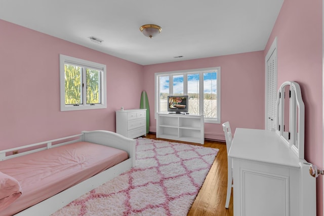 bedroom with light hardwood / wood-style floors and multiple windows