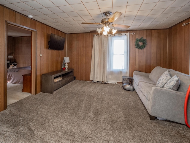 living room with light carpet, ceiling fan, and wooden walls