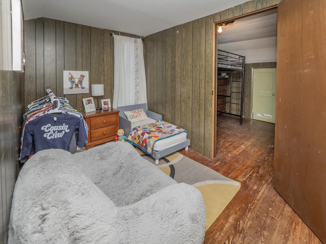 bedroom with dark wood-type flooring and wooden walls