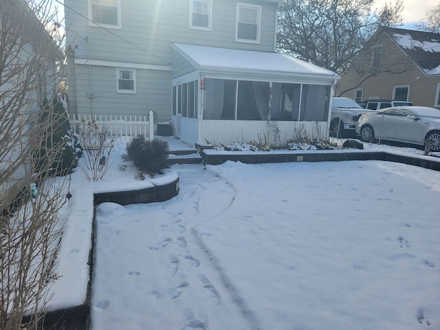 snow covered house featuring a sunroom