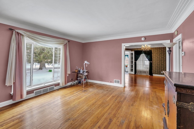 empty room featuring wood-type flooring, crown molding, and a chandelier