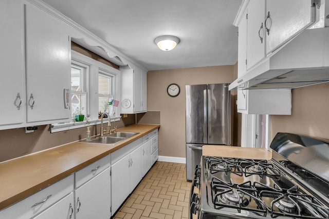 kitchen with white cabinetry, gas stove, stainless steel fridge, and sink