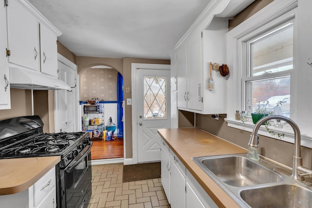 kitchen featuring black gas range, white cabinets, and sink