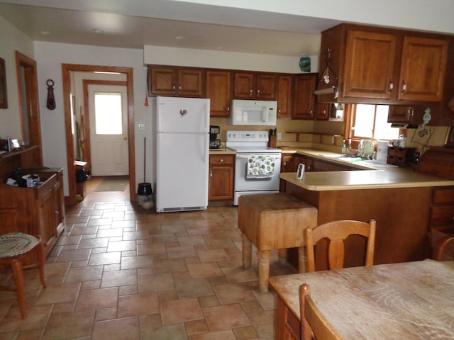 kitchen with white appliances, brown cabinetry, and a sink