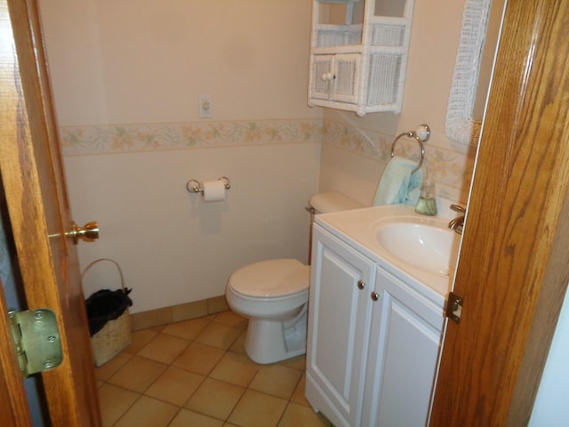 half bath with toilet, vanity, and tile patterned flooring