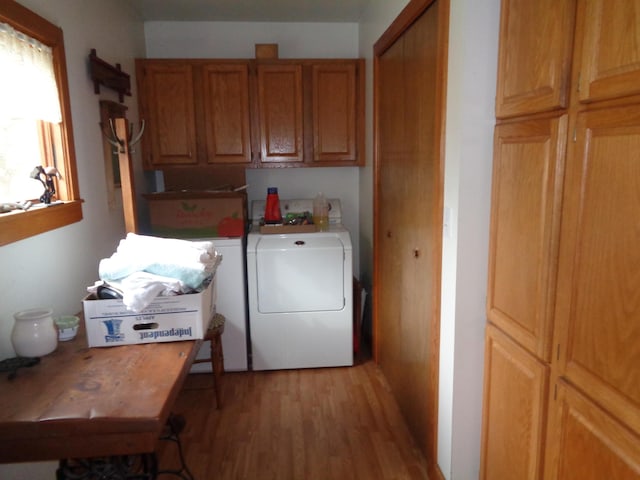 washroom with light wood-type flooring, cabinet space, and washing machine and dryer