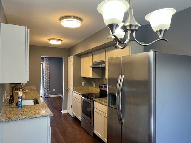 kitchen featuring decorative light fixtures, sink, stainless steel appliances, white cabinets, and light stone counters