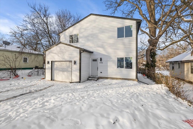 snow covered rear of property featuring a garage