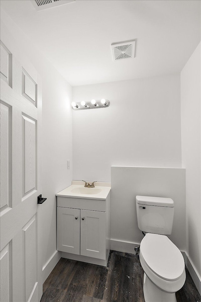 bathroom featuring toilet, hardwood / wood-style flooring, and vanity