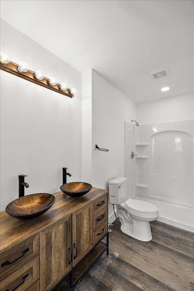 bathroom with hardwood / wood-style floors, toilet, vanity, and walk in shower