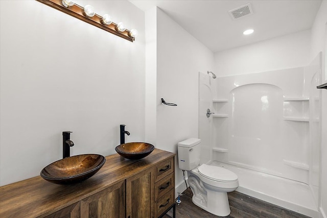 bathroom with toilet, vanity, wood-type flooring, and a shower