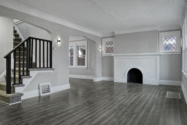 unfurnished living room with a fireplace, dark hardwood / wood-style flooring, and a textured ceiling