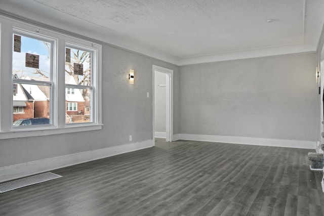 spare room featuring dark wood-type flooring and a textured ceiling