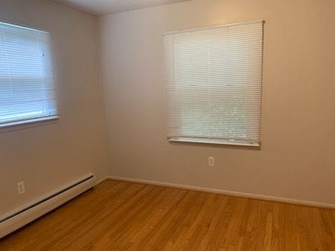 unfurnished room featuring hardwood / wood-style flooring and a baseboard radiator