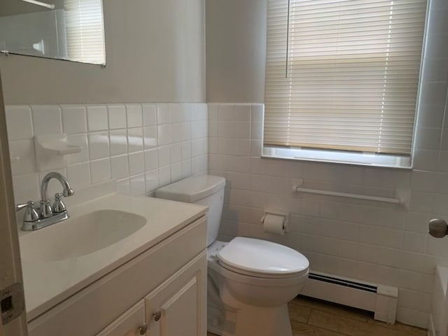 bathroom with toilet, a baseboard heating unit, tile walls, tile patterned floors, and vanity