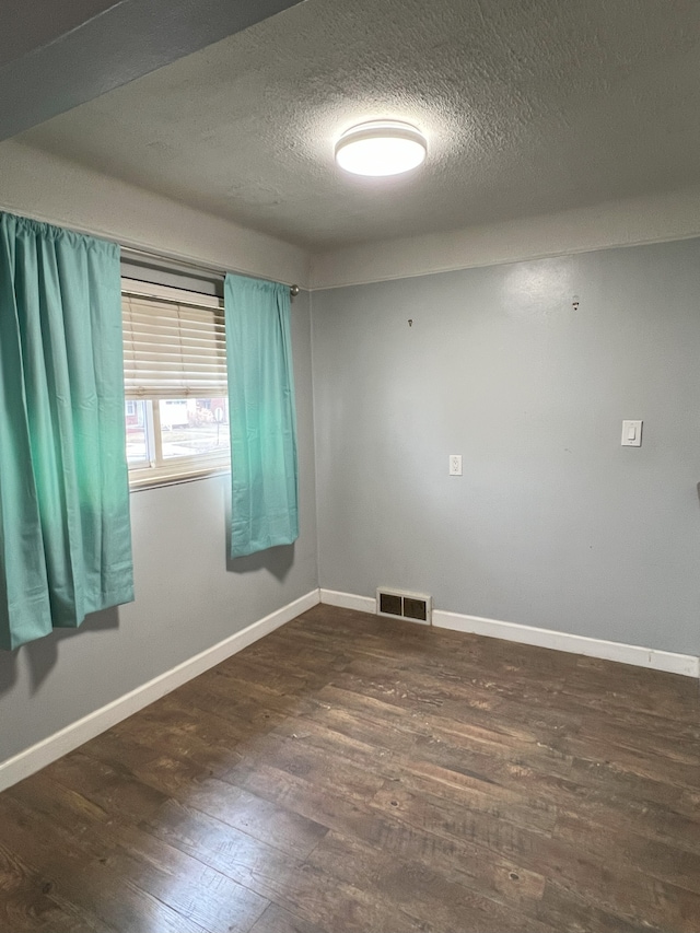 unfurnished room with a textured ceiling and dark hardwood / wood-style flooring